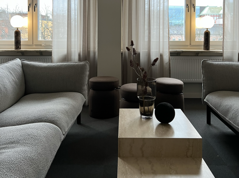 Två grå soffor står mitt emot varandra i gemensam yta i Two´s lokaler. I mitten, ett bord med moderna detaljer.